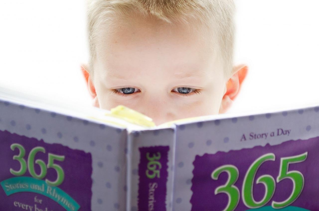 Niño leyendo muy de cerca un libro grande de cuentos