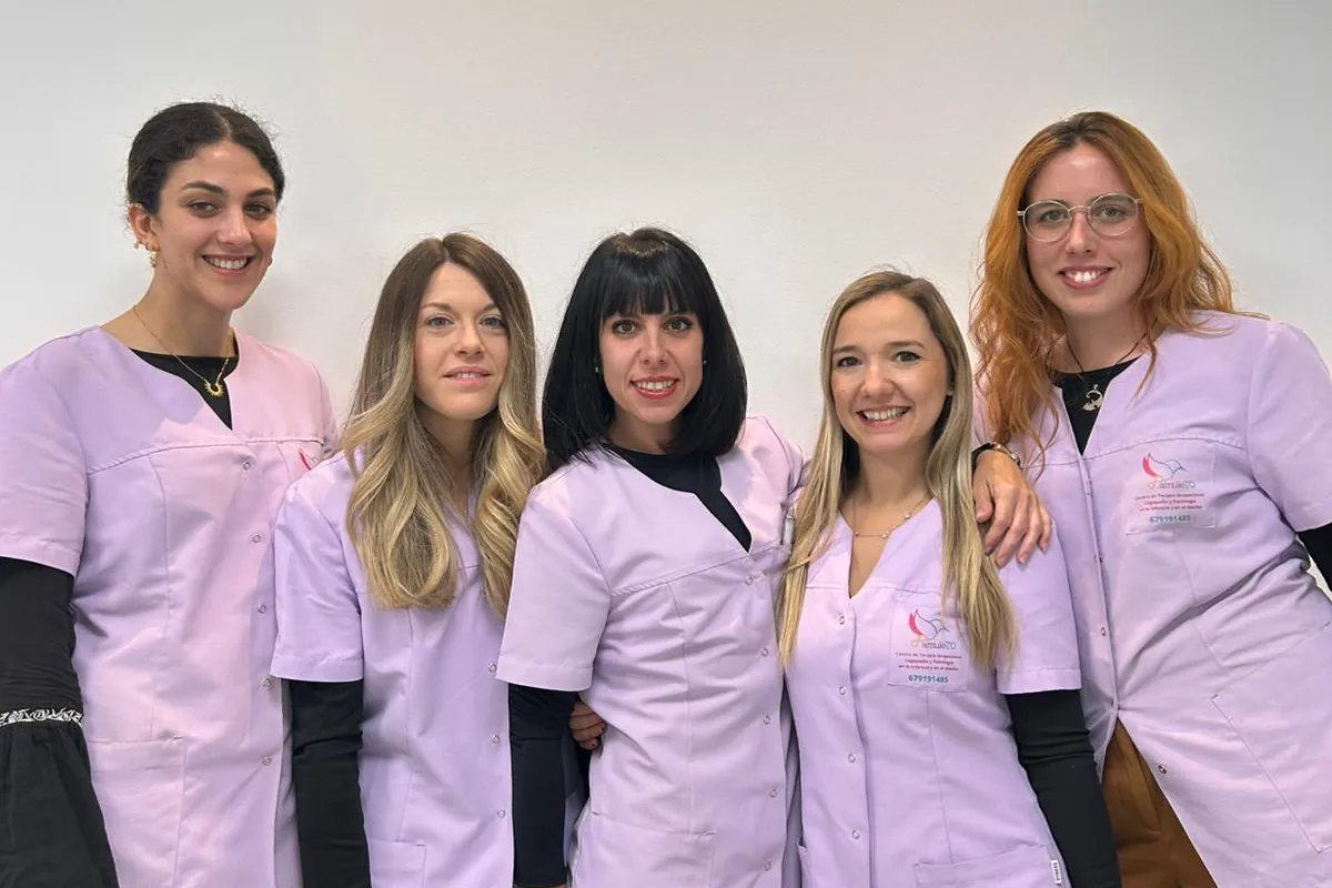 El equipo de AmuleTO: cinco profesionales con el uniforme lila del centro, sonriendo delante de una pared blanca